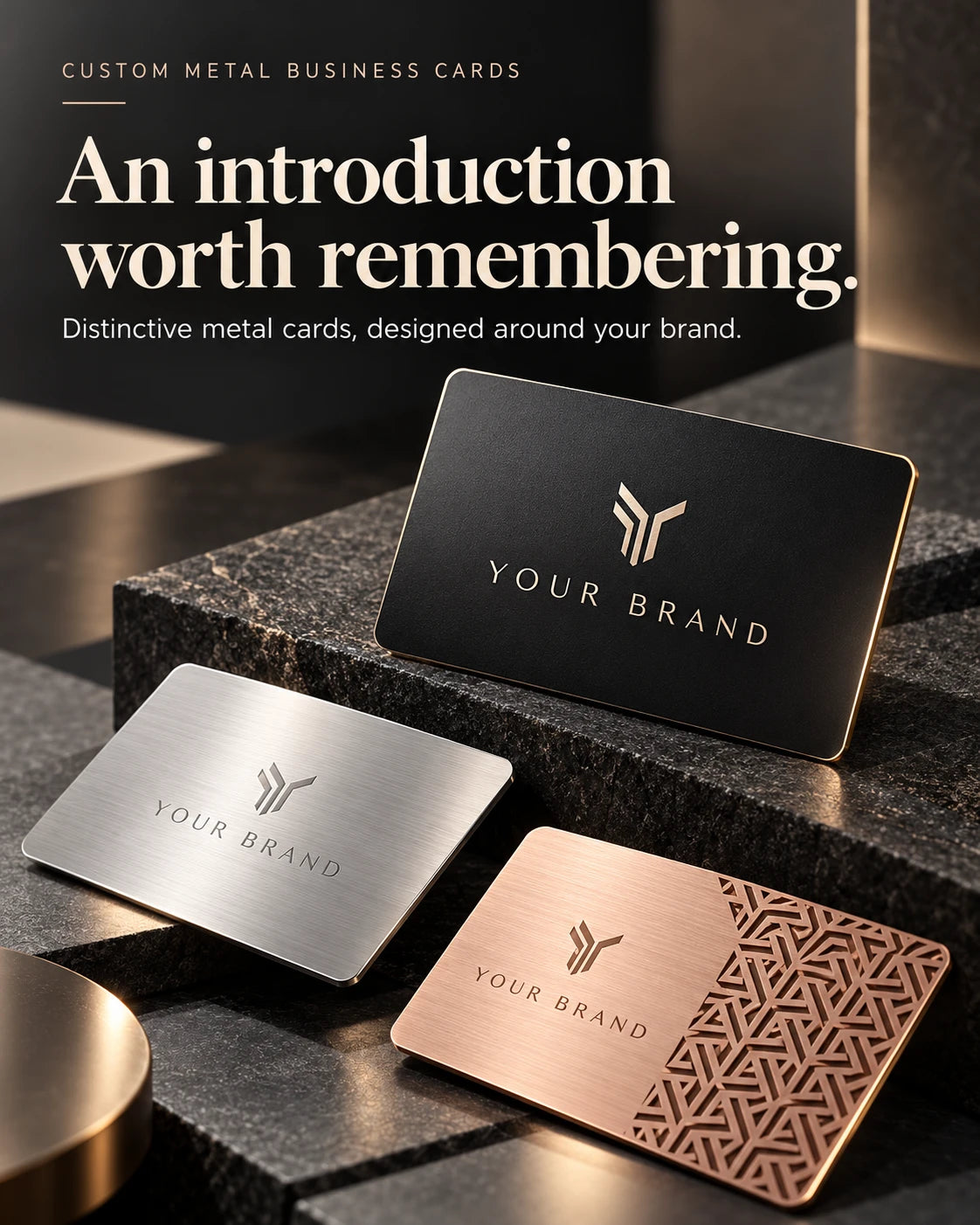 Black, silver-tone and rose-gold-tone metal business cards with custom logos displayed on dark stone blocks