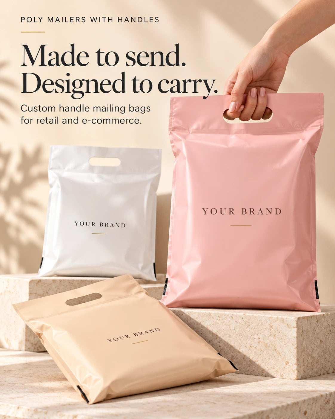 Hand holding a pink branded handle mailer bag beside white and beige bags displayed on cream stone platforms