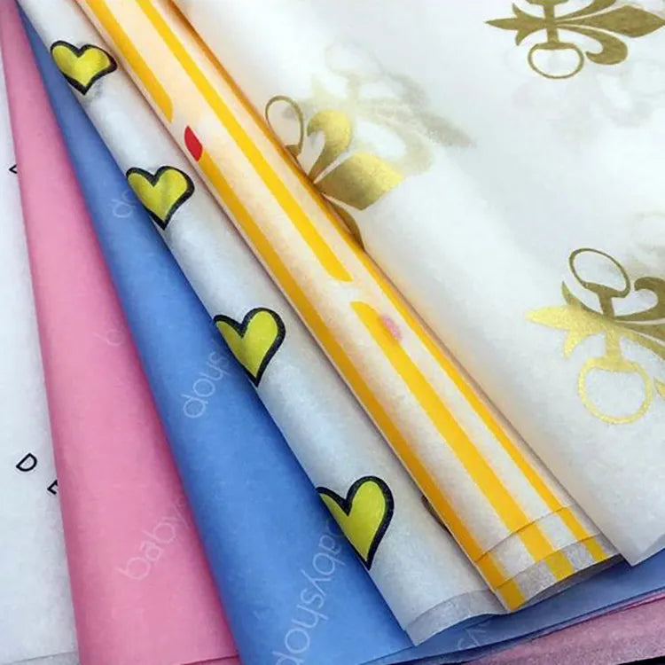 Layered pink, blue and white tissue paper with yellow hearts, stripes and gold decorative motifs