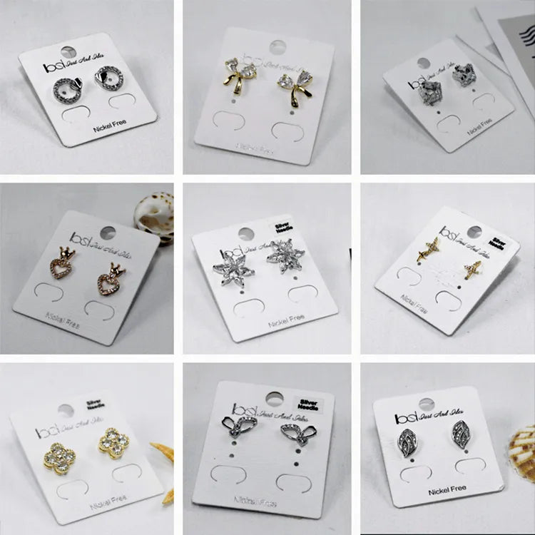 Nine white stud earring cards display grid with assorted rhinestone studs showing clean pre-punched mounting holes