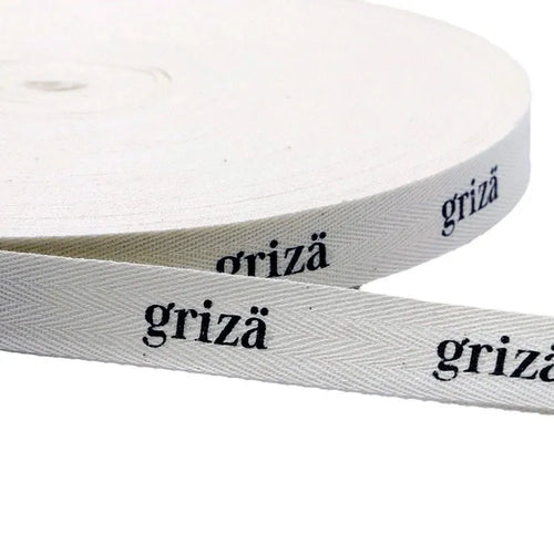 White herringbone cotton twill tape roll printed with black brand lettering for clothing labels