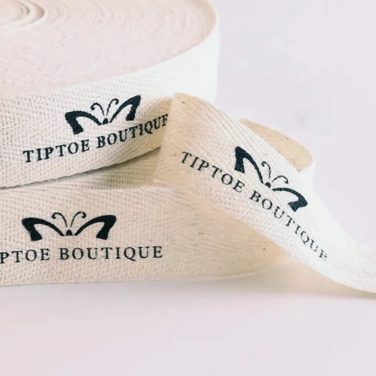 Cream herringbone cotton tape printed with custom butterfly emblem and boutique brand name