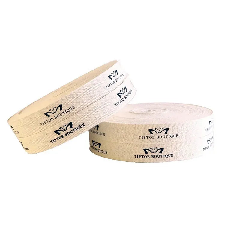 Two rolls of cream herringbone cotton ribbon printed with boutique brand emblem and wordmark