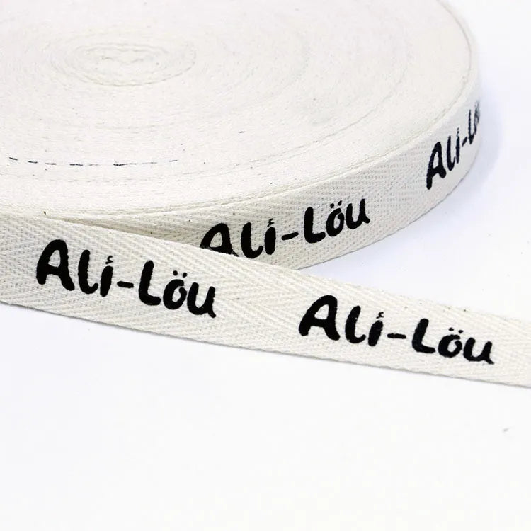 White herringbone cotton tape roll printed with continuous black script brand signature