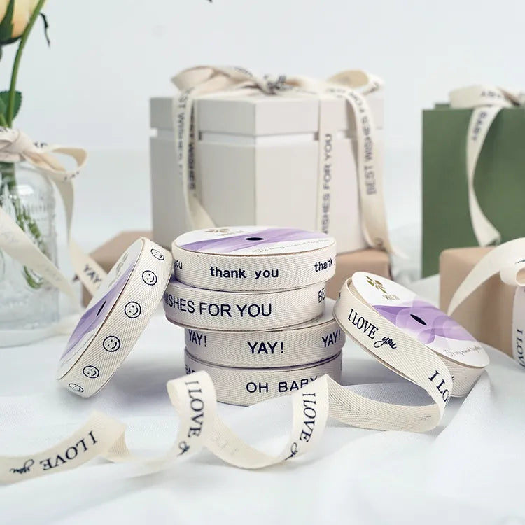 Printed cream cotton ribbon rolls displayed beside gift boxes tied with matching ribbon