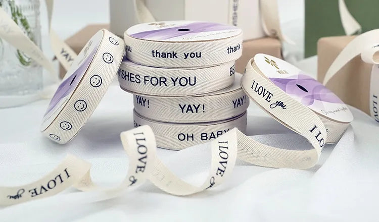 Natural white cotton ribbon spools with custom printed brand messages for gift and retail packaging