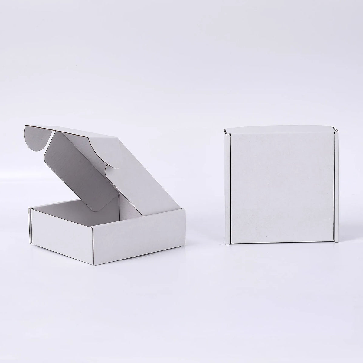 Open and closed plain white mailer boxes on a white background