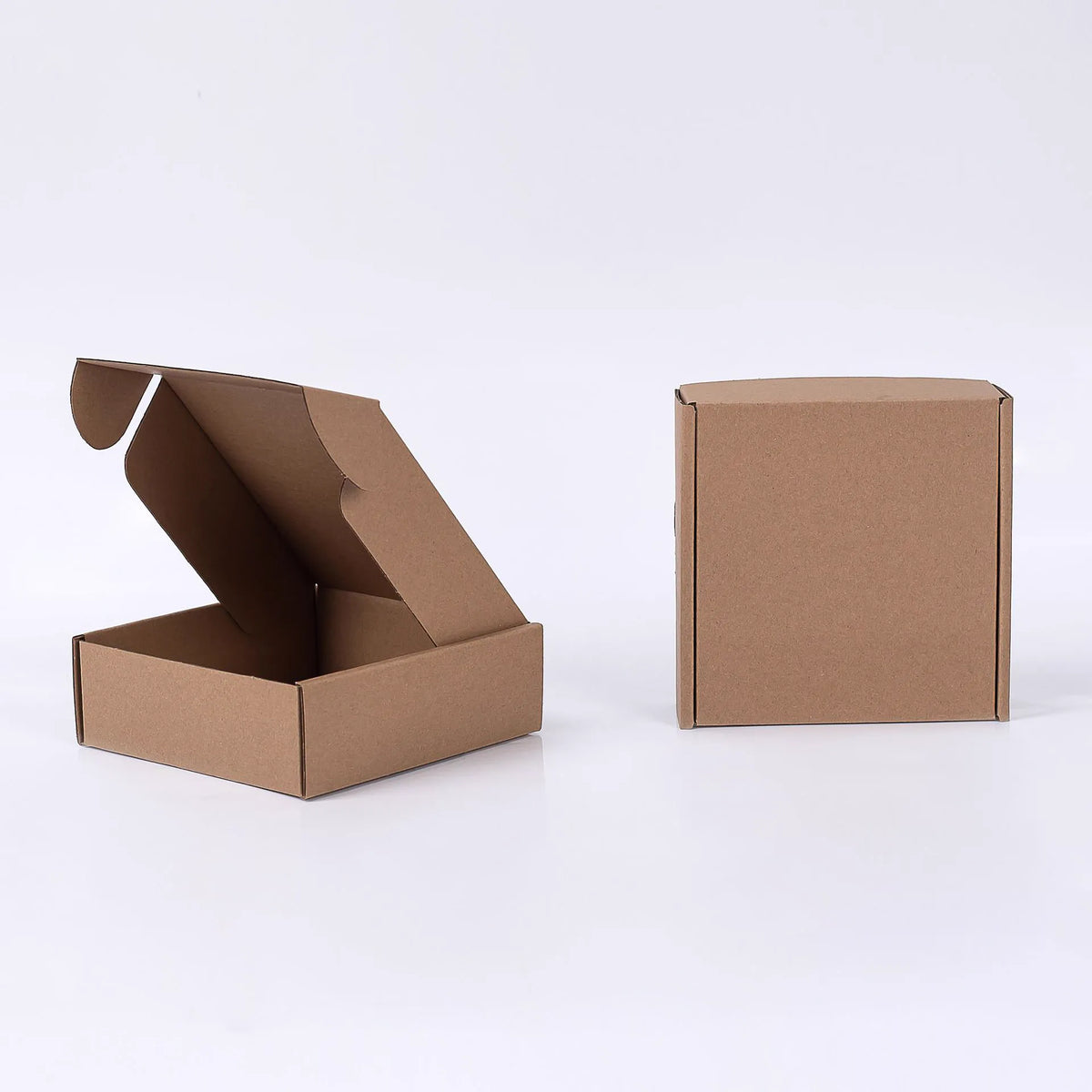 Open and closed plain brown kraft mailer boxes on a white background