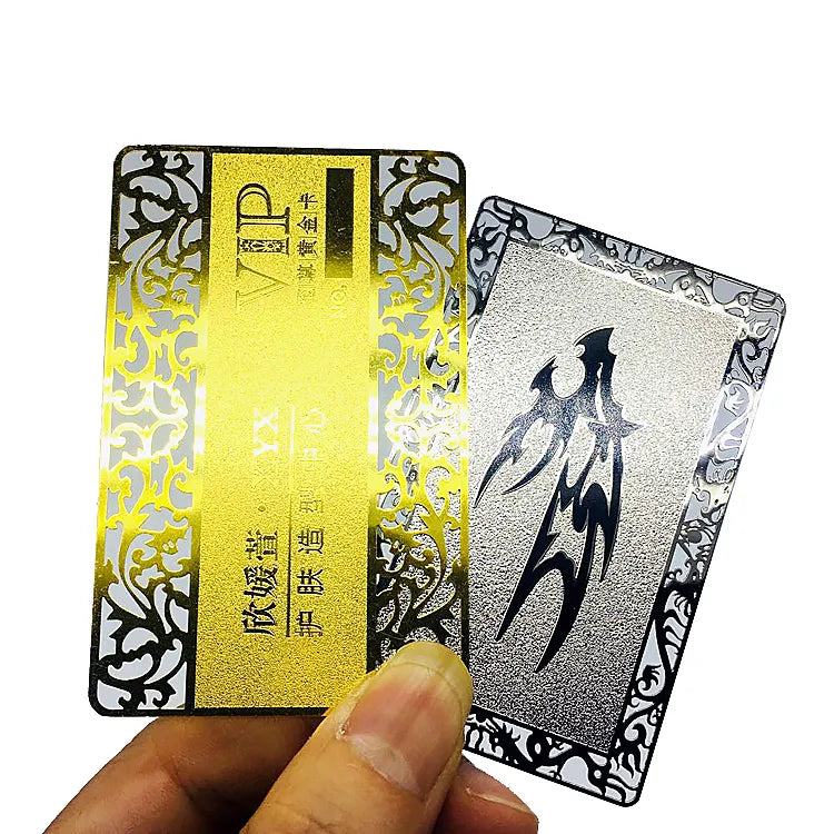 Decorative metal business cards in gold and silver tones with dark lettering and patterned edges