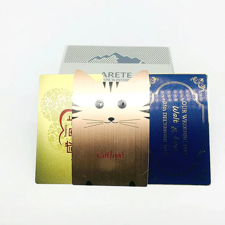 Gold-tone, silver-tone and blue metal business cards displayed upright with printed brand artwork
