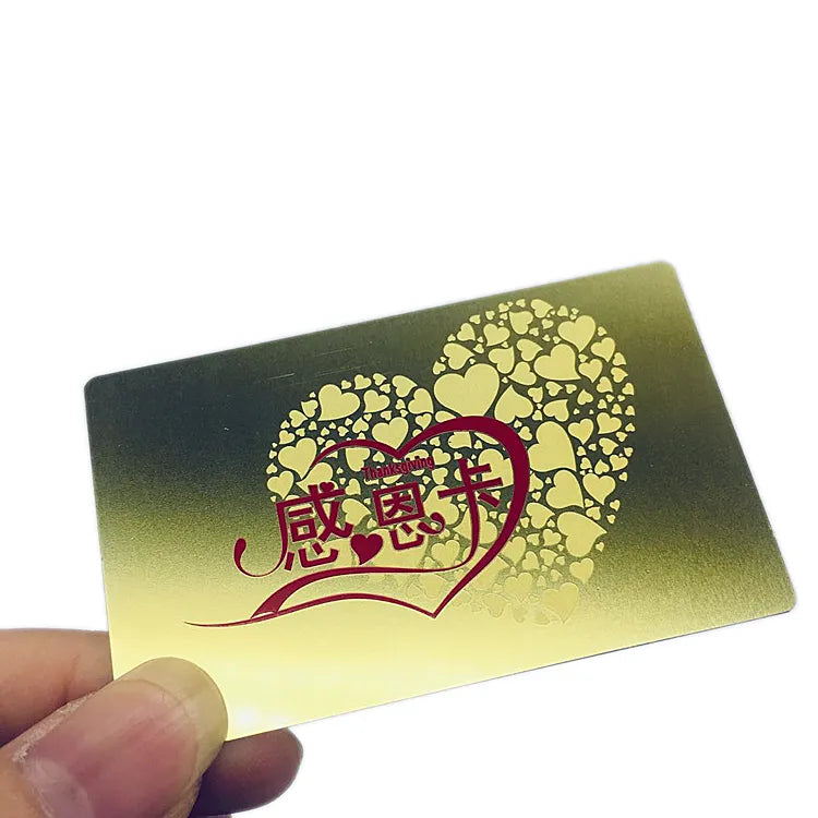 Gold-tone metal business card with a decorative red tree design and patterned openwork