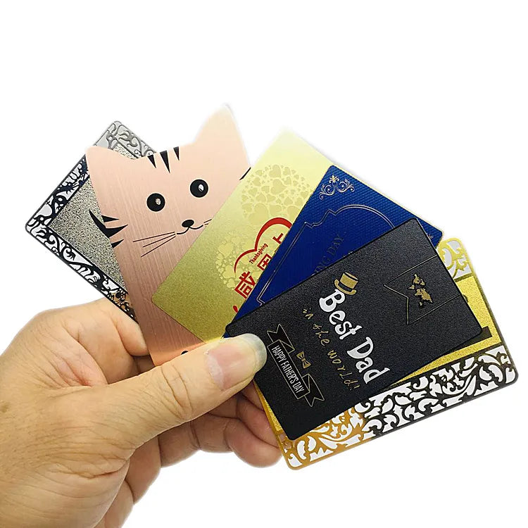 Hand holding a fan of metal business cards in silver, gold, rose-gold and dark finishes