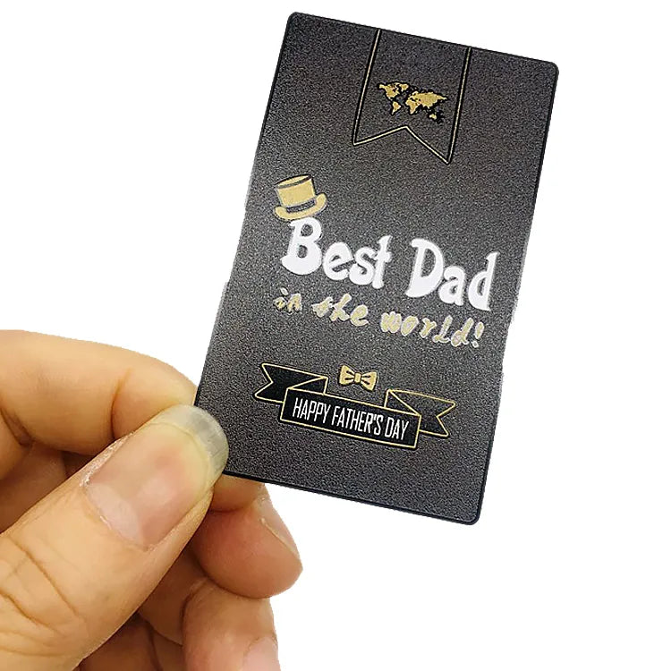 Black metal business card with contrasting Bed Dad lettering held in one hand
