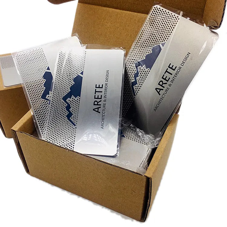 Silver-tone printed metal business cards packed in an open cardboard box