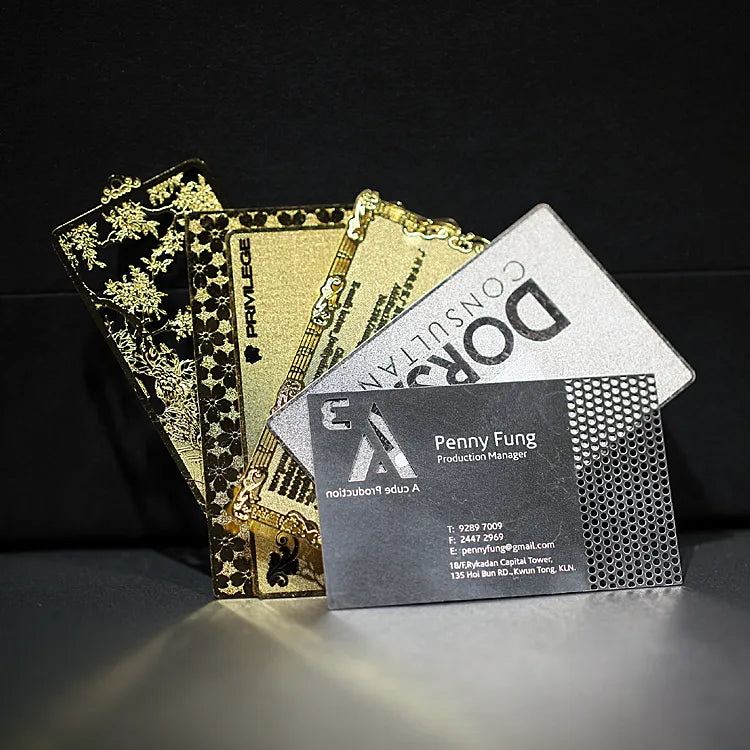 Black, gray and gold-tone metal business cards fanned out on a dark background
