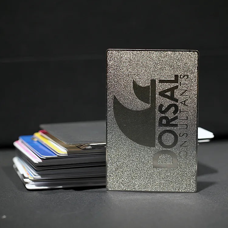 Gray metal business card with ORSAL lettering displayed beside a stack of cards