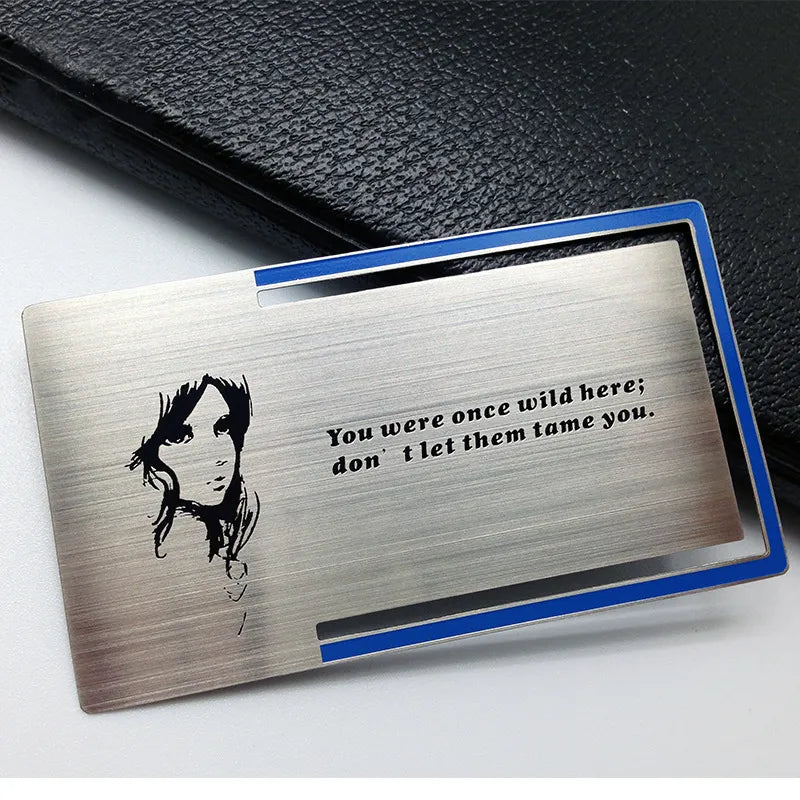 Silver-tone metal business card with a black portrait illustration displayed in a blue-edged presentation case