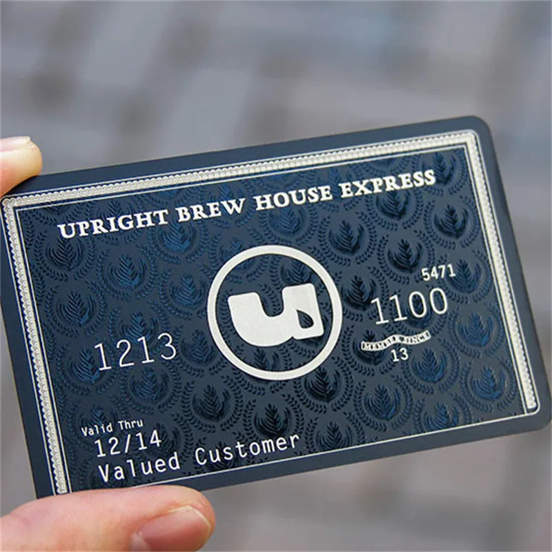 Black metal membership card with white lettering and numbering held in one hand