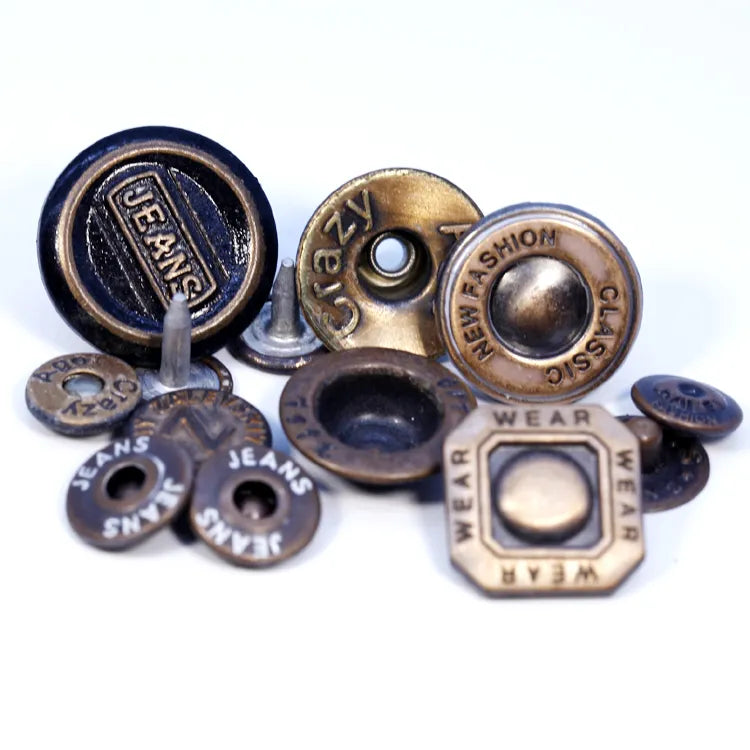 Alloy metal jeans shank button with embossed CALOMDS brand lettering mounted on blue denim fabric