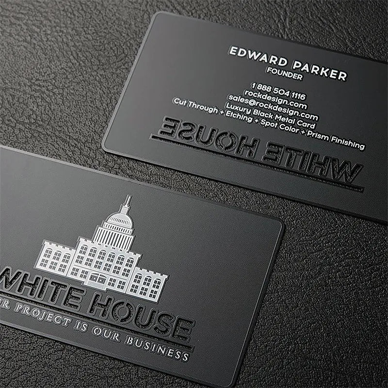 Two dark metal business cards with white building artwork and contact lettering