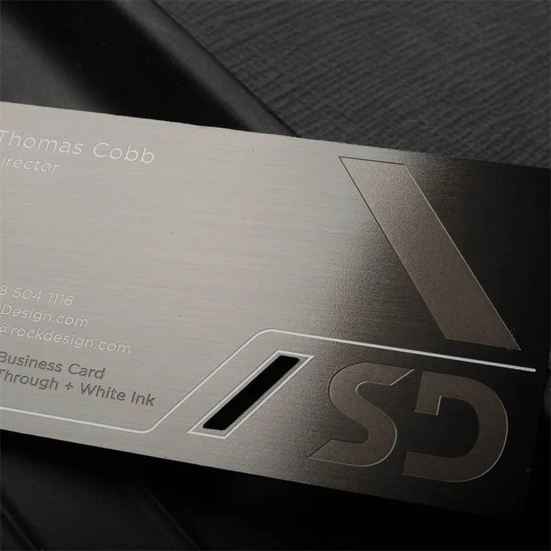 Gray metal card showing a broad reflective face, dark decorative markings and rounded corners