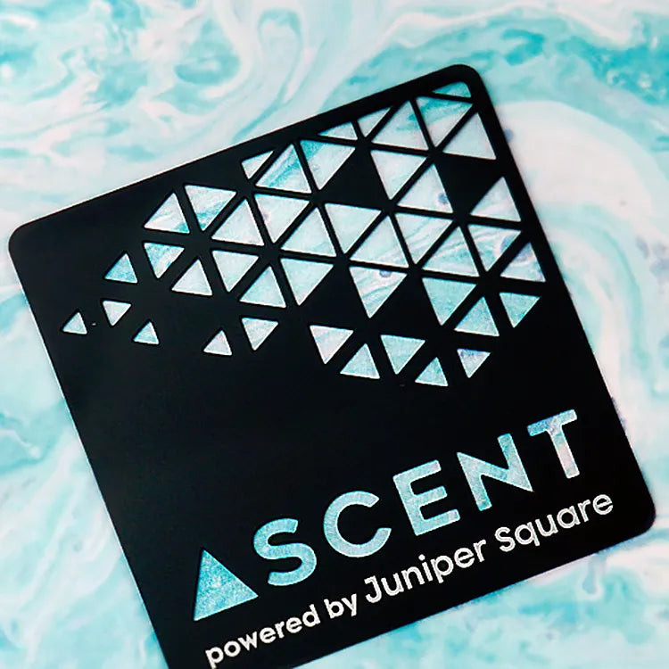Black metal business card with triangular cutouts and ASCENT lettering on a turquoise background