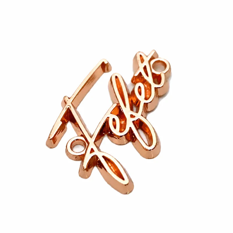 Small gold floral script metal tag for knitwear and crochet measuring 11mm by 38mm
