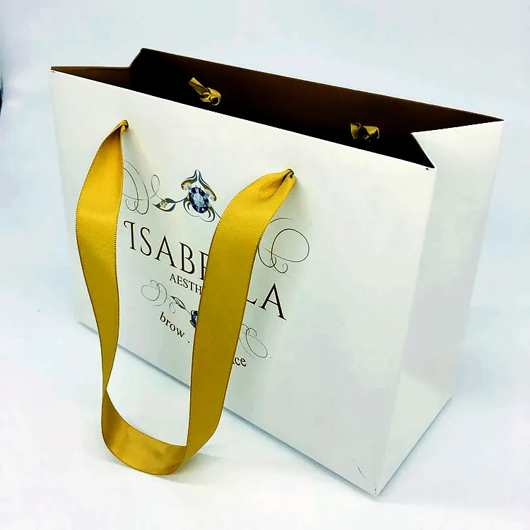 White paper gift bag with yellow ribbon handles and a dark inner surface