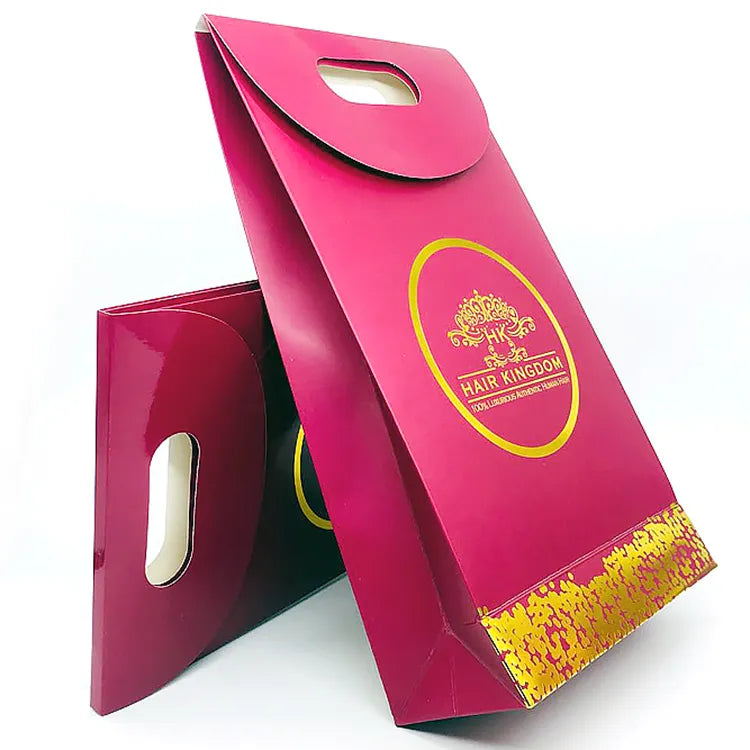 Pink paper bag with a die-cut handle and a gold-colored circular logo