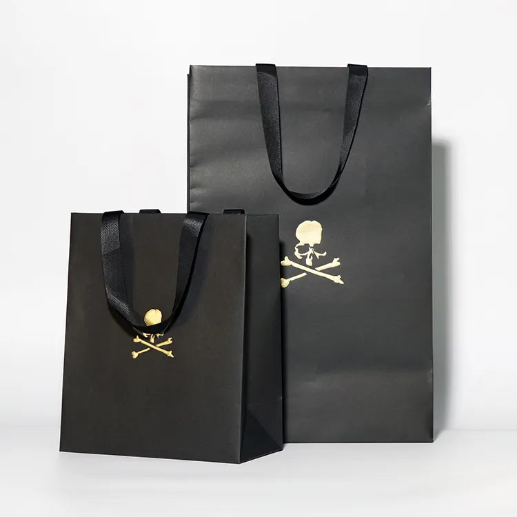 Black paper shopping bags in two sizes with a gold-colored logo and cord handles