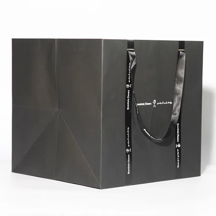 Black paper shopping bag shown from the side with cord handles