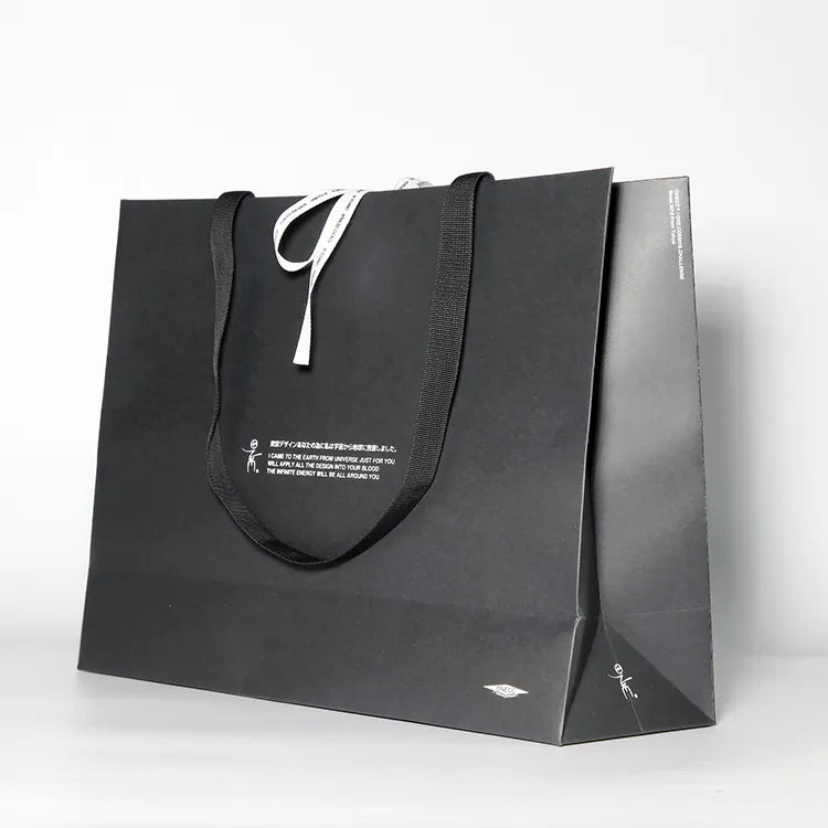 Black paper shopping bag with pale cord handles and a small central logo