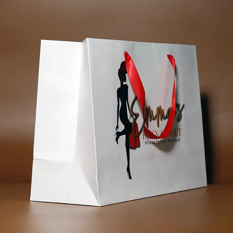 White paper shopping bag with red ribbon handles and decorative printed graphics