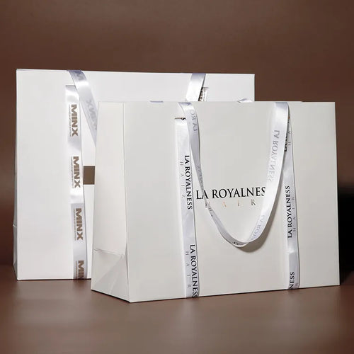 White paper shopping bags in several sizes with pale cord handles on a brown background