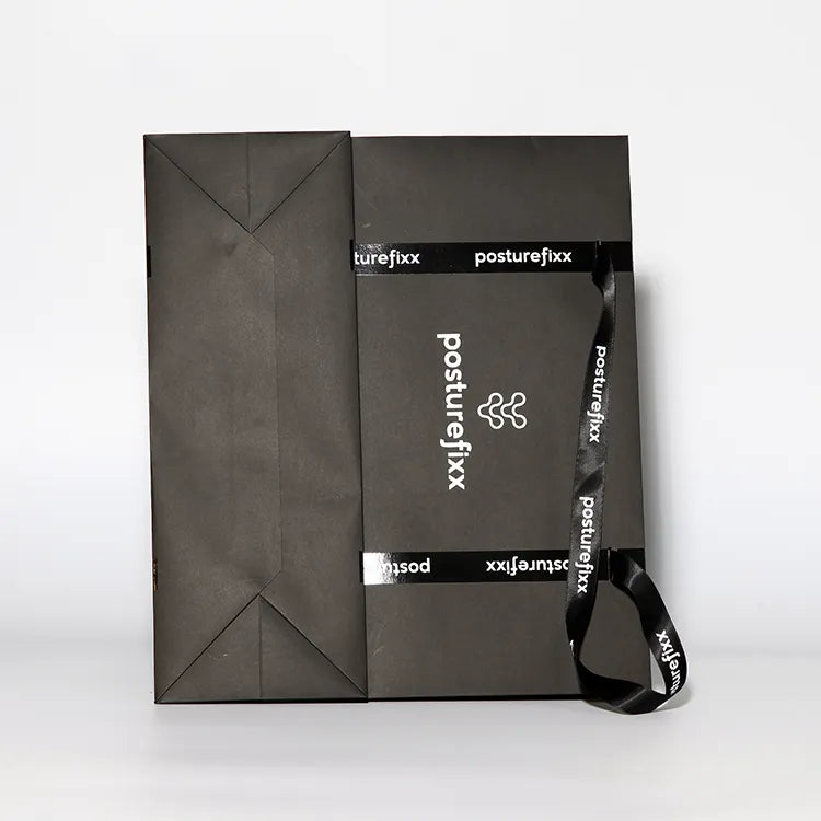 Dark paper shopping bag lying flat with cord handles and a central printed logo