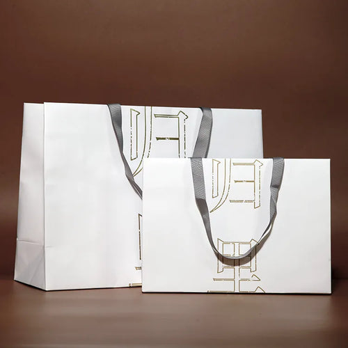 White paper carrier bags with cord handles displayed together in several sizes