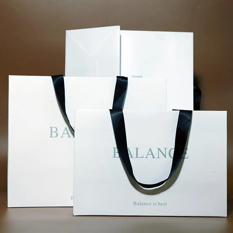 Two white paper shopping bags with wide black ribbon handles