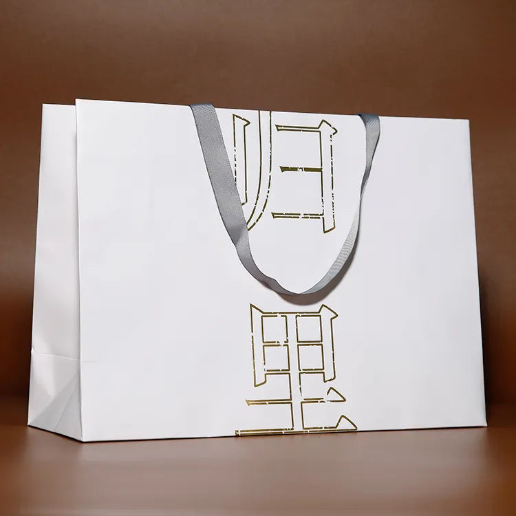 White paper shopping bag with light cord handles and a thin outlined graphic