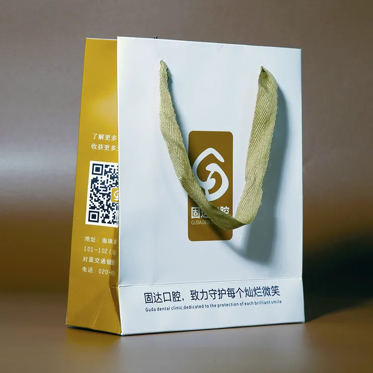 White paper bag with yellow side panels, green handles and a central printed emblem