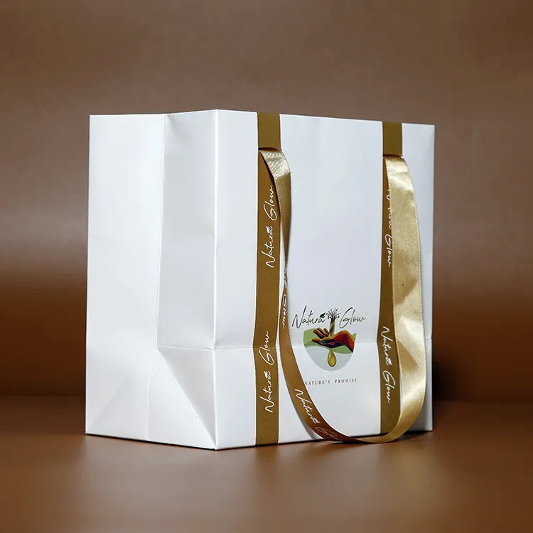 White paper carrier bags with gold-colored ribbon handles displayed side by side