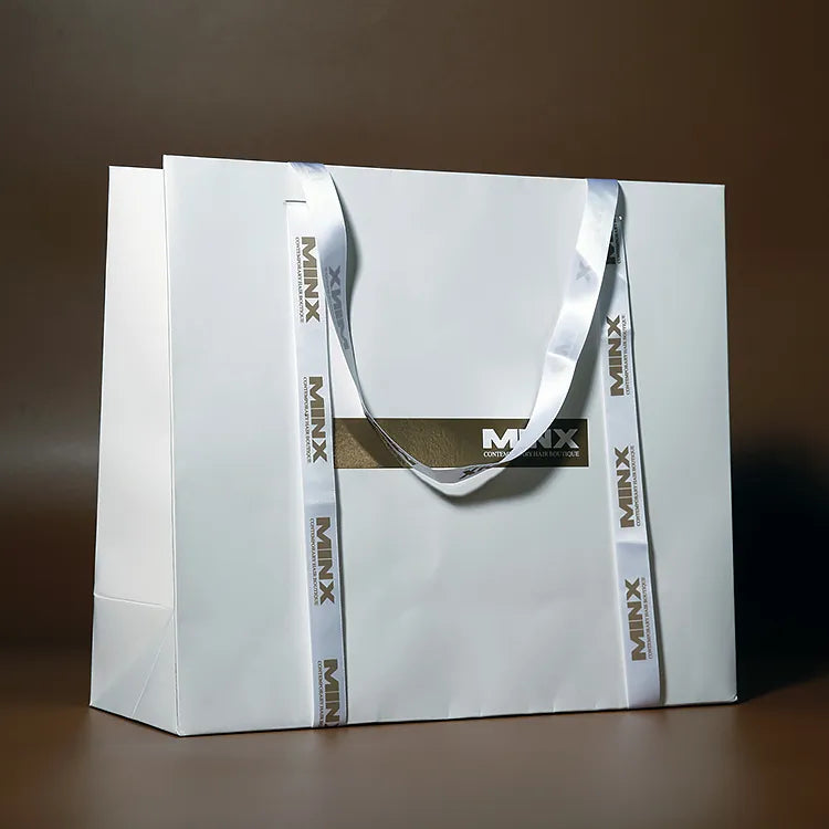 White paper carrier bag with contrasting ribbon handles and decorative vertical print