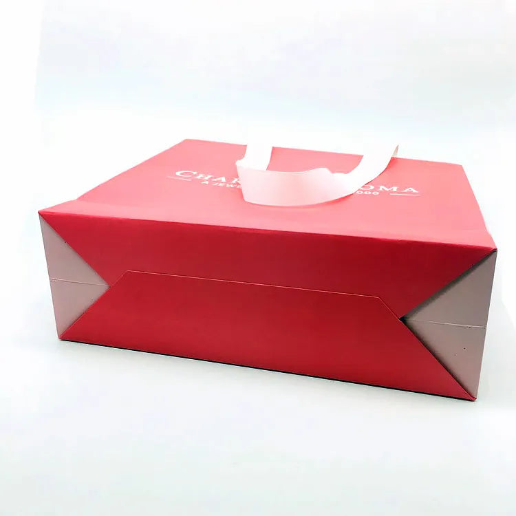 Pink paper bag lying on its side with a folded bottom and pale handle