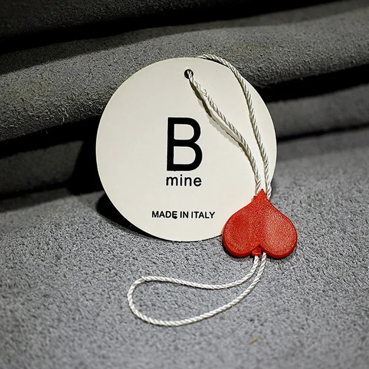 Round white printed hang tag with white twisted cord and red heart-shaped string seal