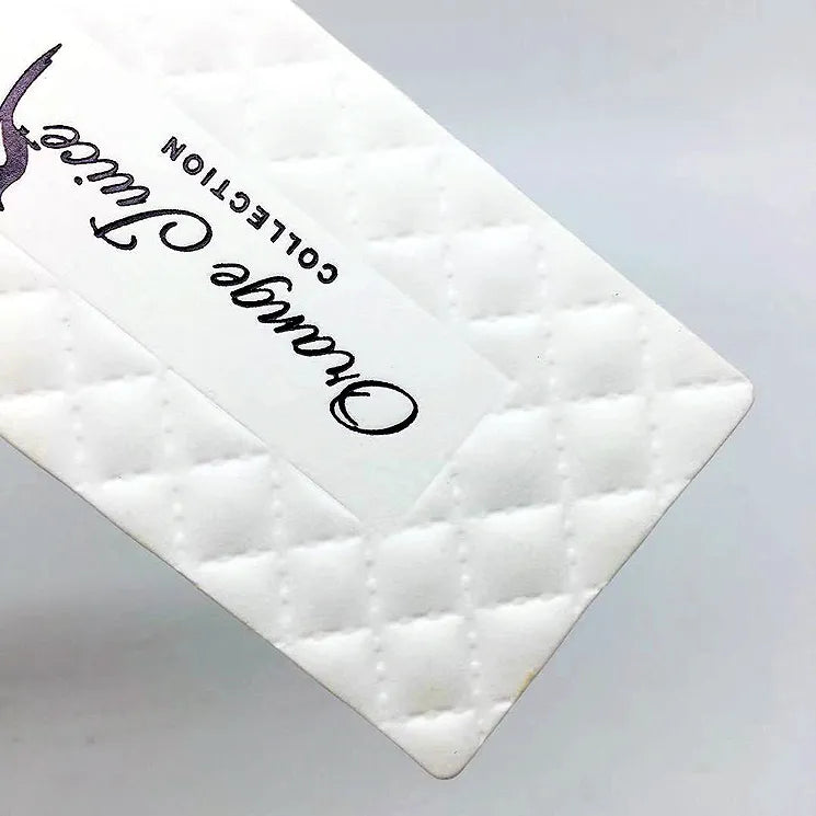 White quilted-texture hang tag with black script lettering and attachment ring