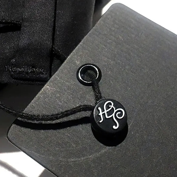 Close-up of grey clothing hang tag with black eyelet, cord and round branded string seal