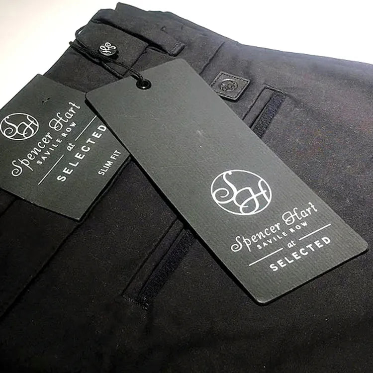 Dark grey rectangular logo hang tag attached to black trousers with black string