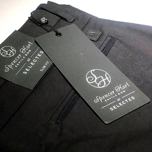 Dark grey rectangular logo hang tag attached to black trousers with black string