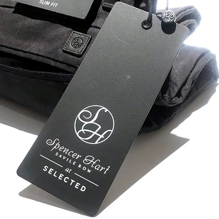 Grey rectangular garment hang tag with white printed branding, black eyelet and branded cord seal