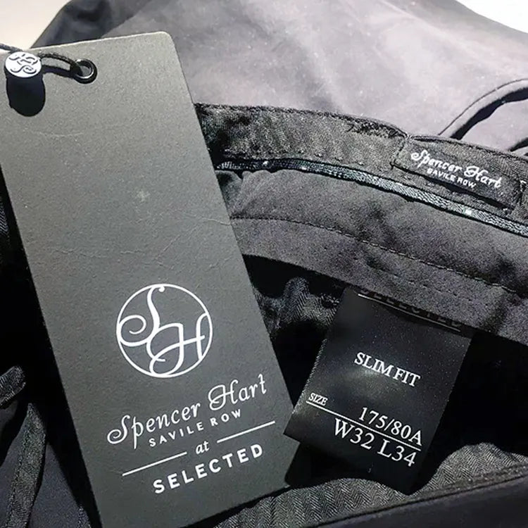 Grey logo hang tag displayed beside black garment size labels and waistband branding
