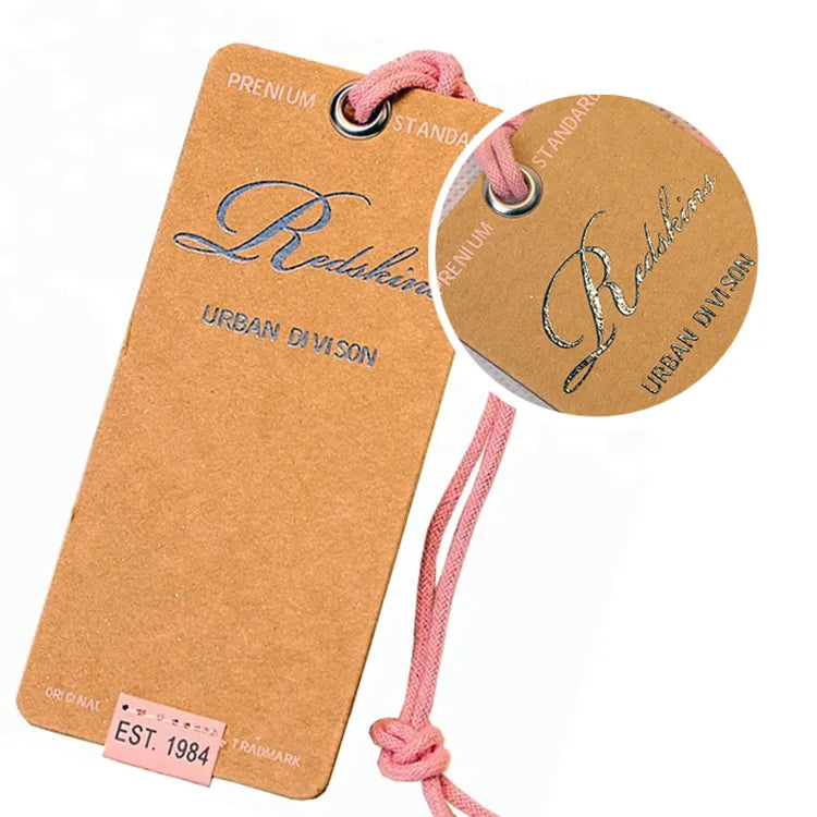Brown rectangular hang tag with metallic script branding, metal eyelet and pink cord detail